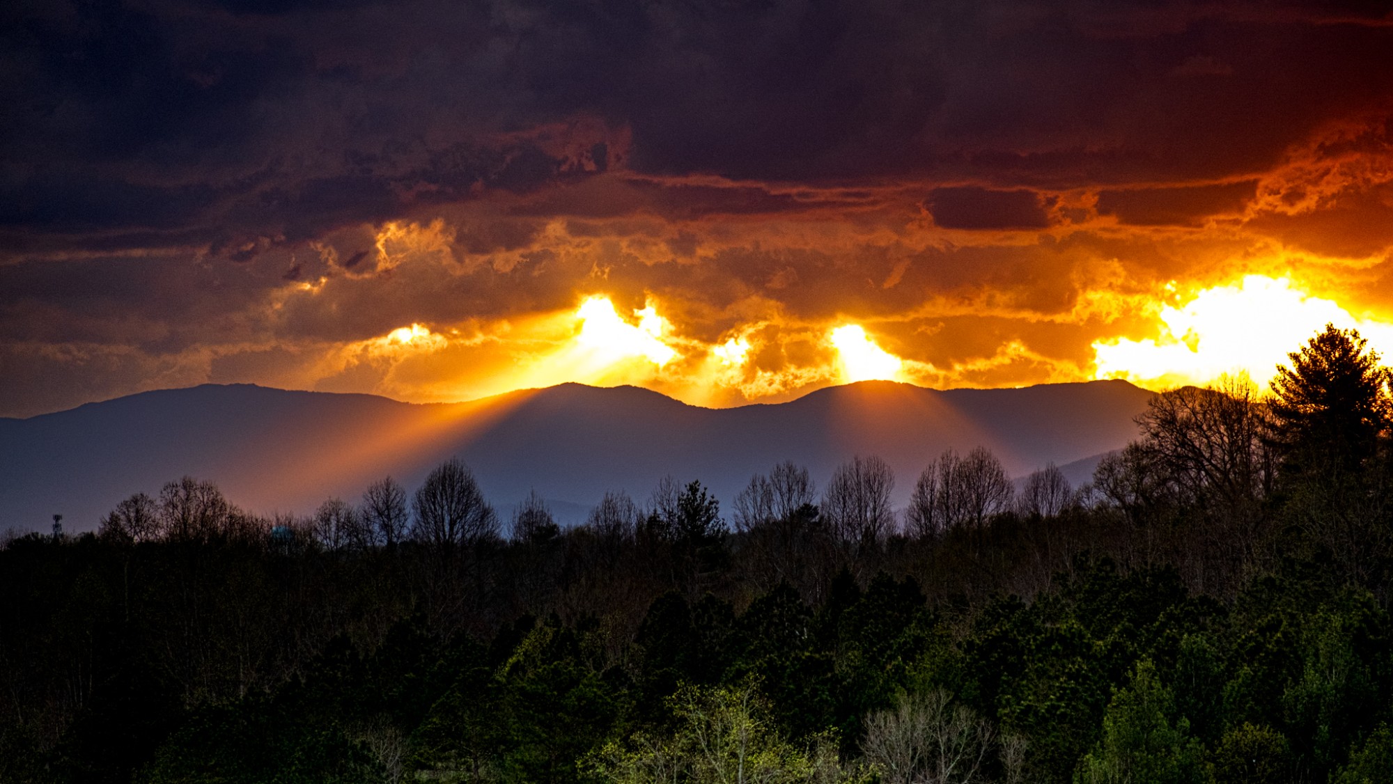 Sun rays breaking through storm clouds over a mountain ridge